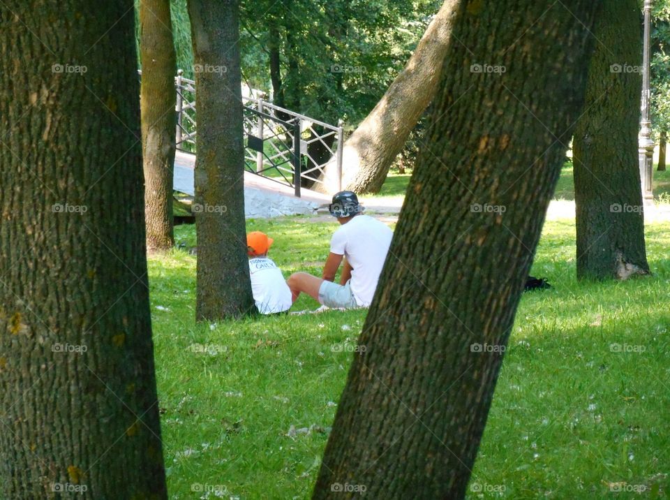 Father and son sitting in a park on the green grass