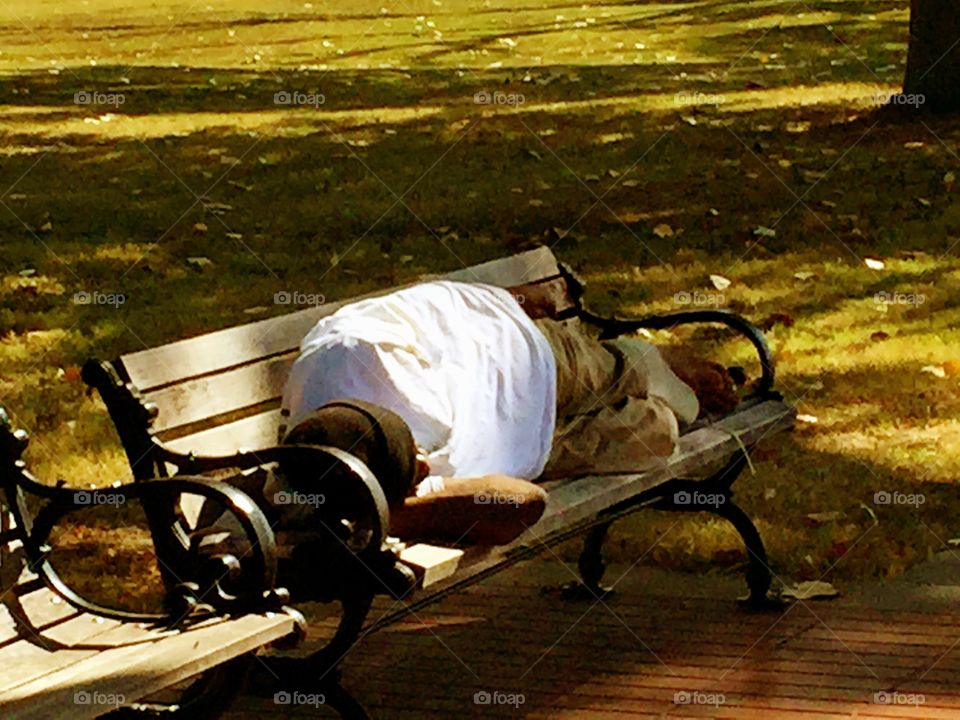 Homeless Man on Park Bench . He was sleeping barefoot with a rolled up news paper as a pillow. God bless him. 