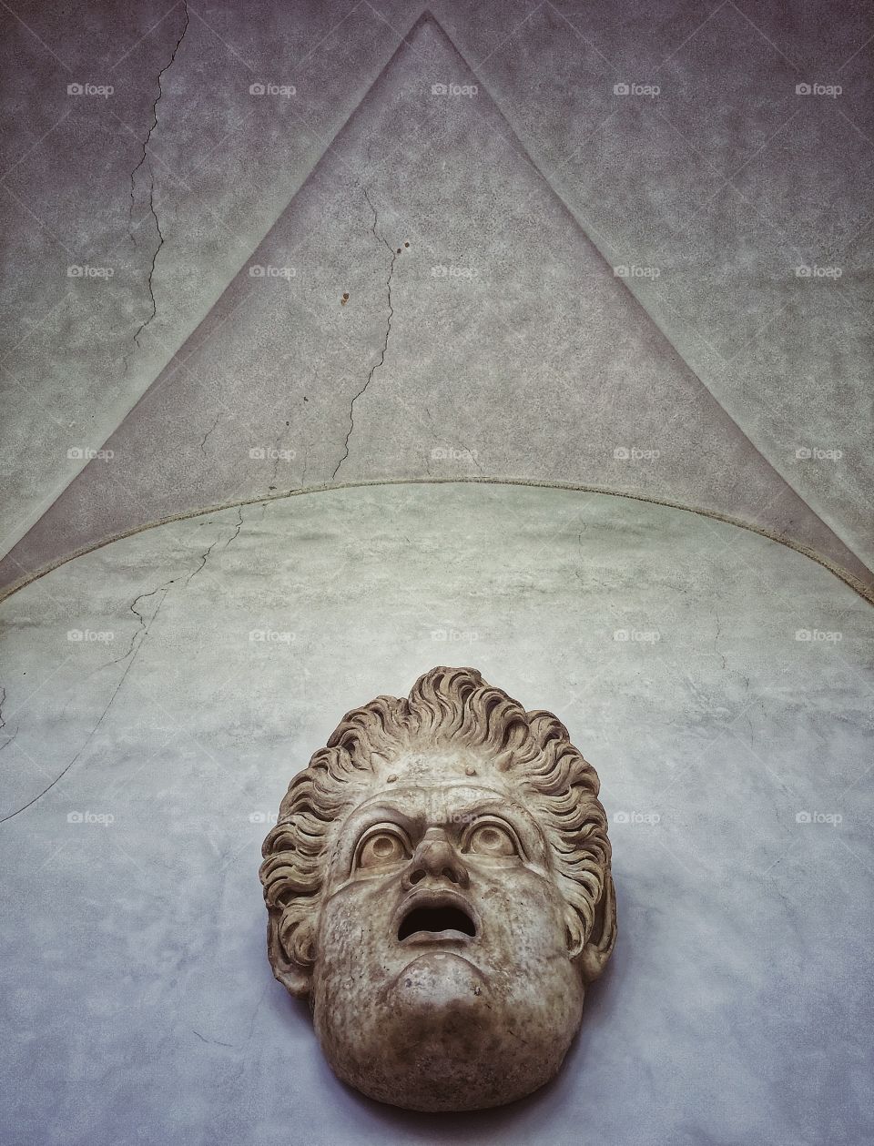 Roman sculpture of a head above a doorway looking up at a vaulted ceiling 