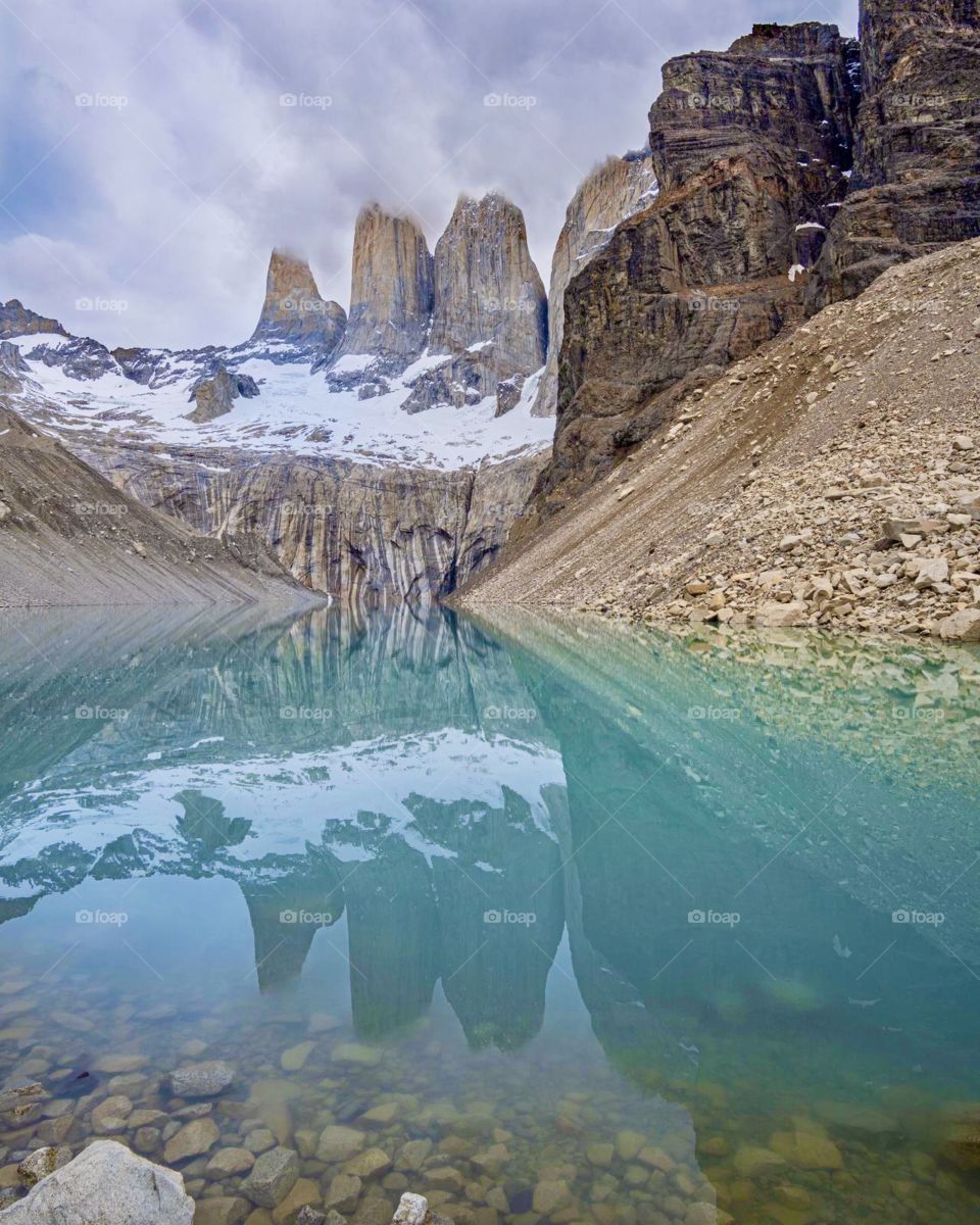 Torres Del Paine towers over the area and is perfectly reflected against the surface of the still lake