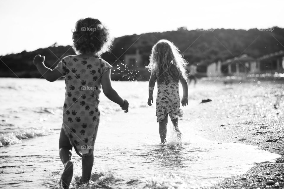 children running on the beach. children running across shallow sea on the beach