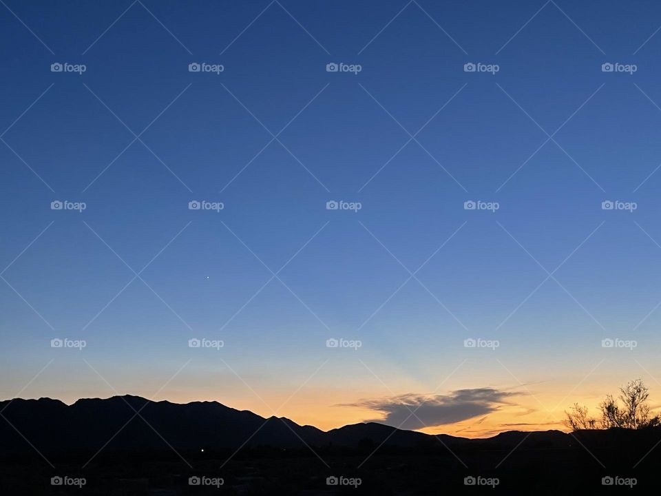 A sunset with mountains and night sky.