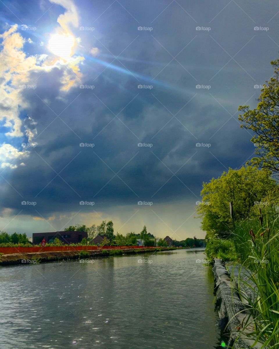 Dark clouds and sun over the river