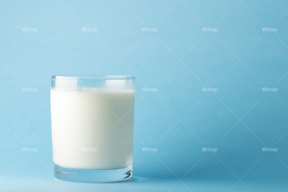 glass of milk on a blue background  . source of calcium and minerals.