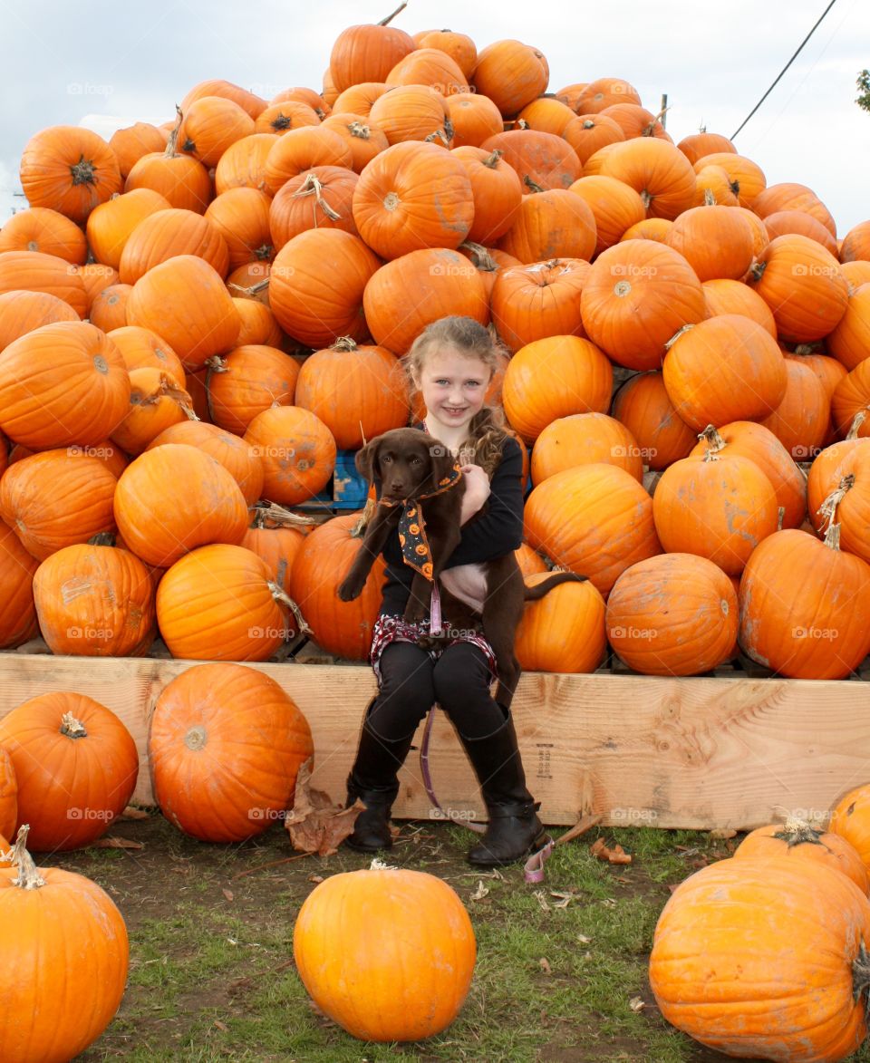 Girl and her dog in a pumpkin pile