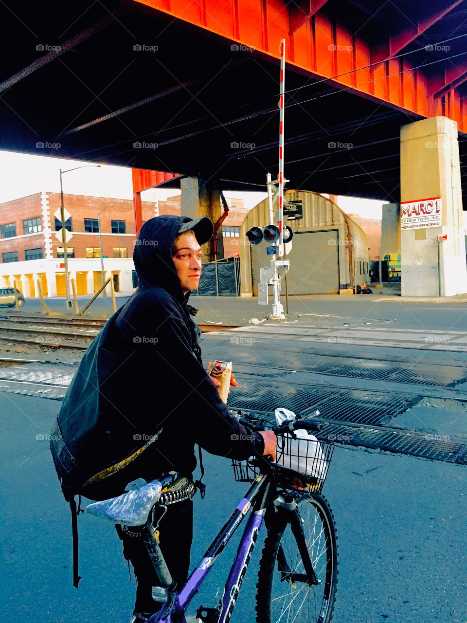 My friend wearing his hoodie on his bicycle by 11th Street and the Pulaski Bridge in Long Island City, Queens, New York photographed in the Spring of 2019. Hypnotic Productions