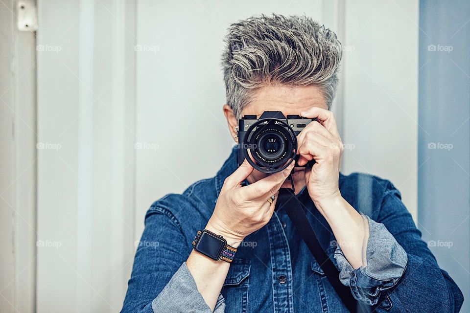 Photographer focuses camera, taking a picture of yourself in the mirror, reflections of a photographer, female photographer takes self portrait 