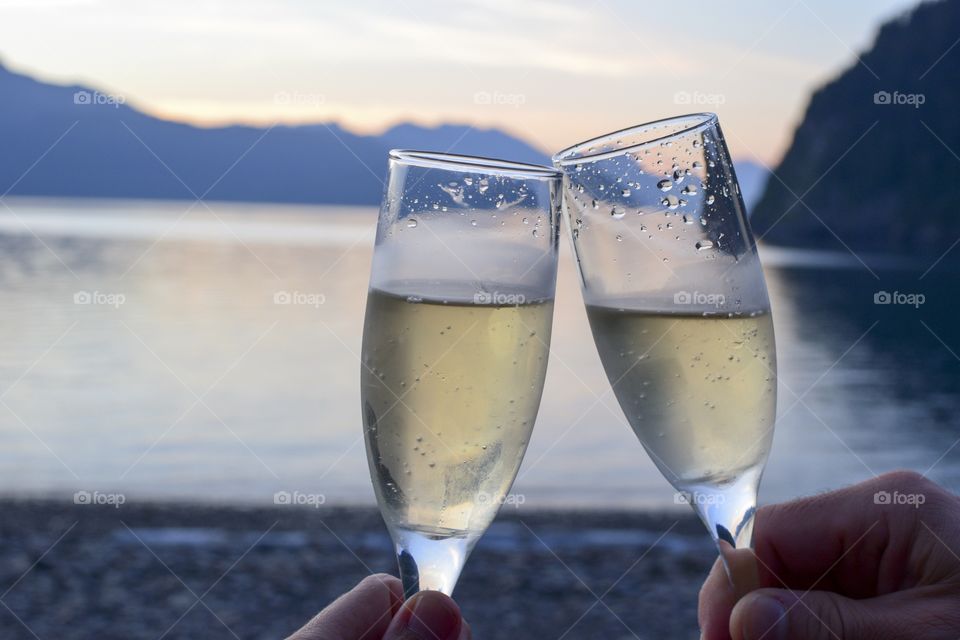 Hands holding and toasting champagne at sunset