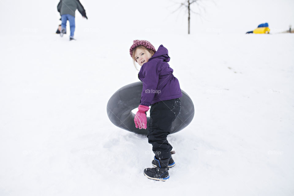 Girl playing in the snow and sledding 