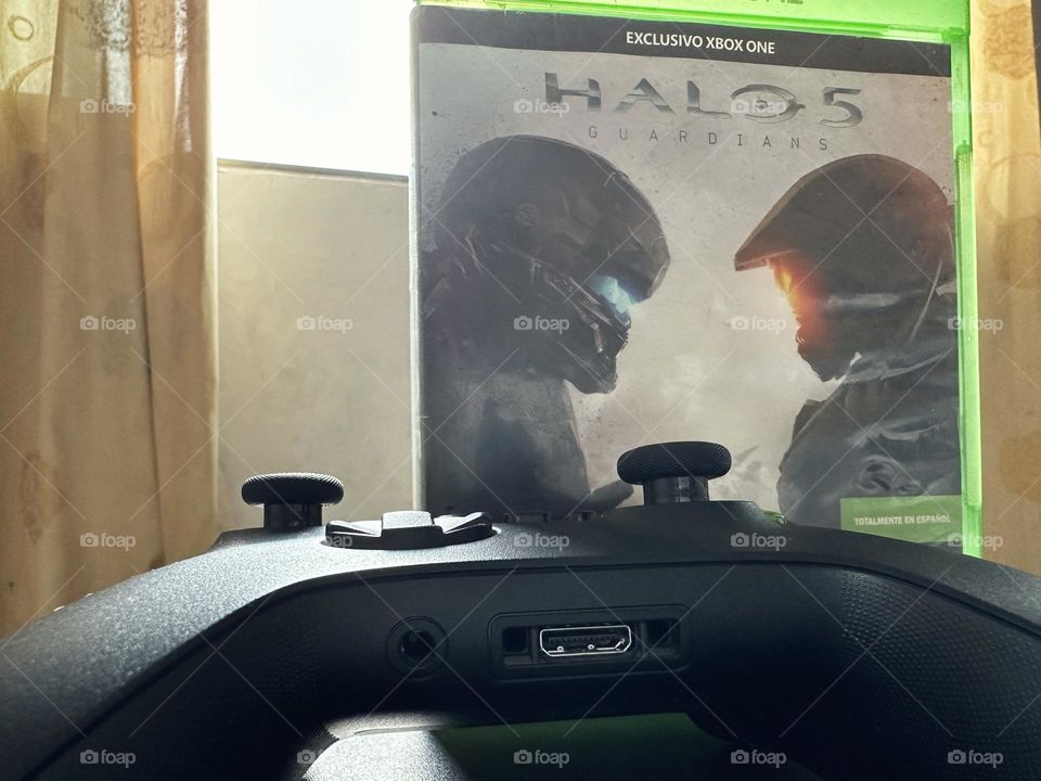 Halo video game box behind of a Xbox controller with natural light at the background.