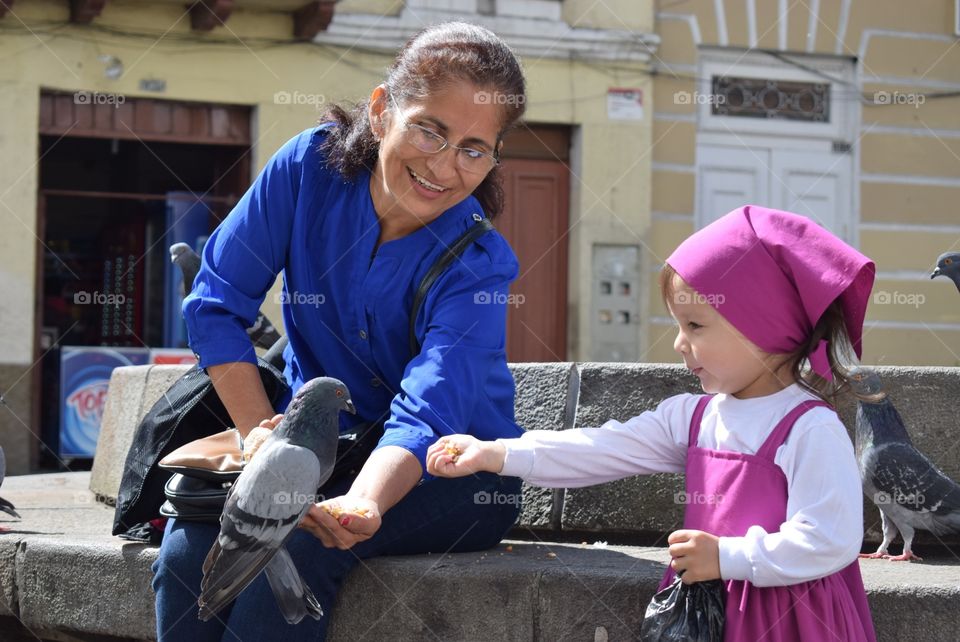 Grandmother and granddaughter feeding pigeons
