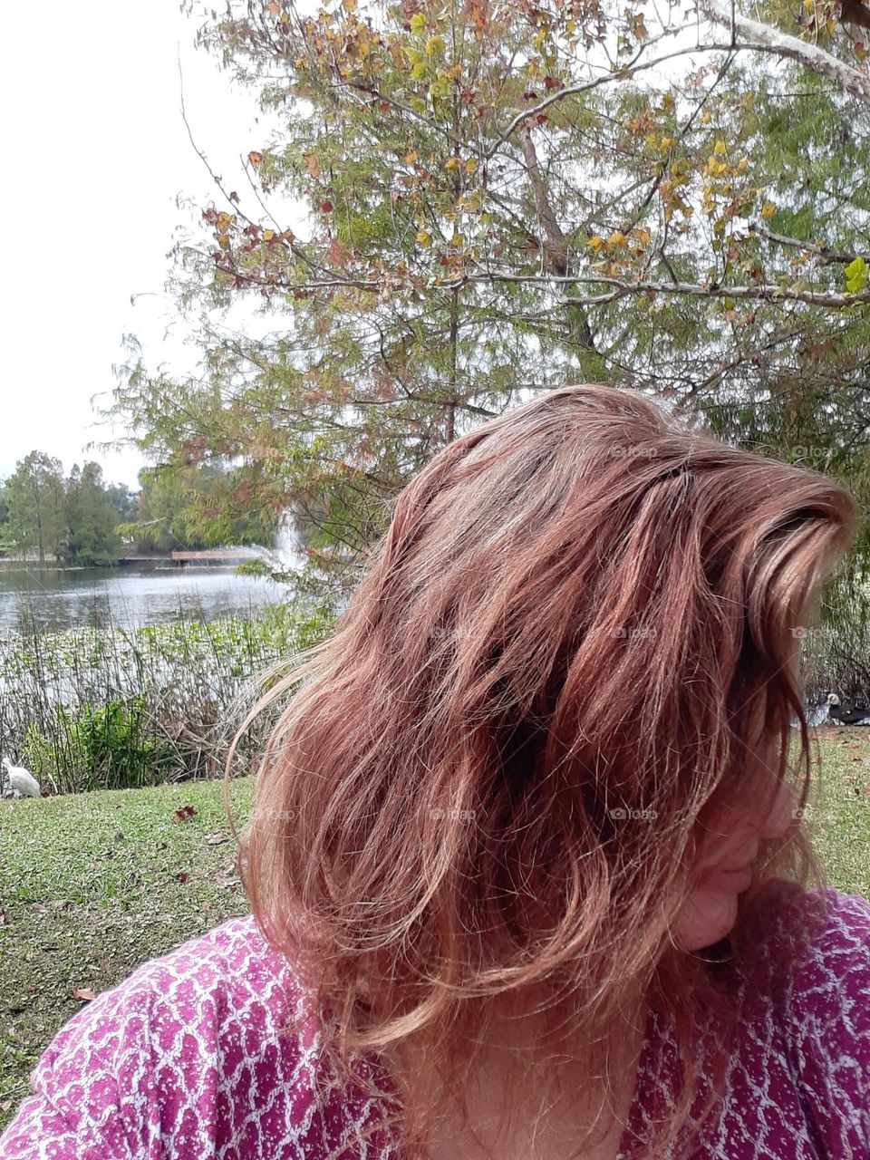 A Caucasian woman with shoulder length brown hair take a selfie at Lake Lily Park.