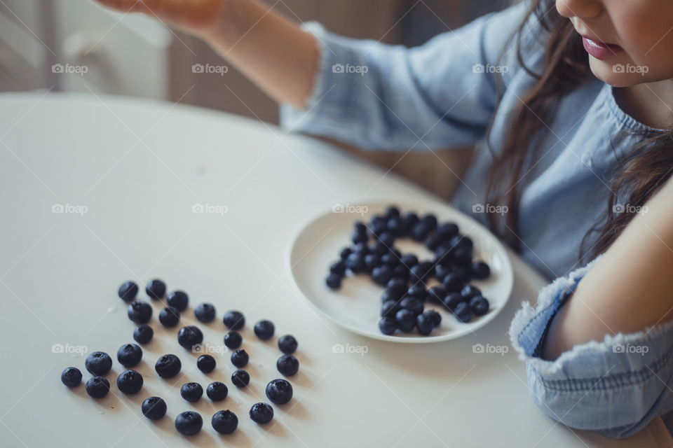 Little girl with blueberries at morning 