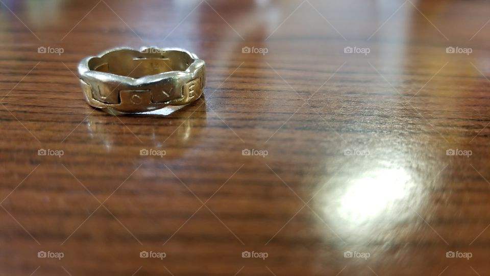 A simple wedding ring left on a wood table, possibly symbolizing a divorce, or the difficulties of marriage.