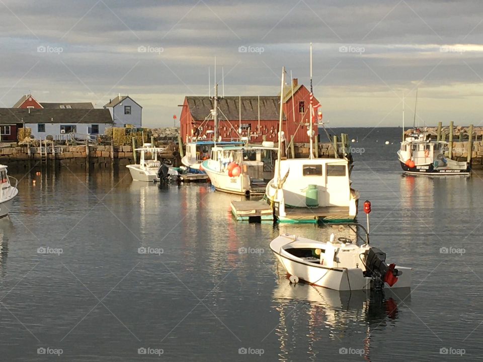 Quintessential charm of coastal Rockport, MA, with a view of fishing boats floating in the tranquil harbor. 