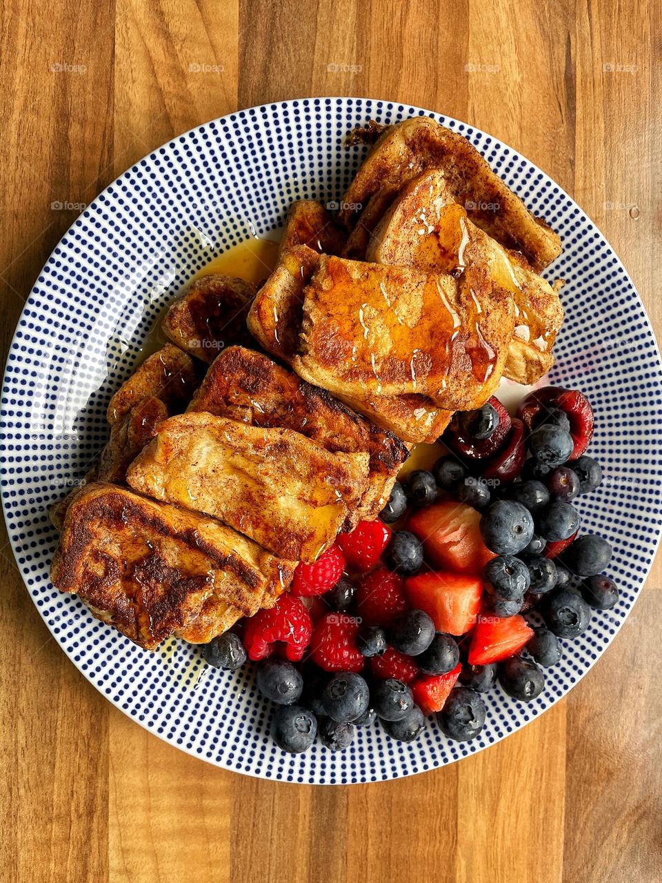 Cinnamon toast with blueberries, raspberries, strawberries and cherries. Drizzled with maple syrup