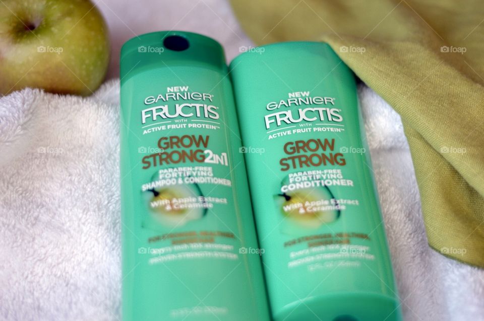 Garnier shampoo and conditioner on a white towel with a green apple in the background