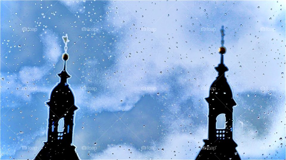 The intense blue partially cloudy evening sky paints beautiful patterns between the outlines of two minaret style onion shaped tower rooftops. This picture was taken in Regensburg, Bavaria, Germany just around Christmas time in 2019. Hypnotic Prod.