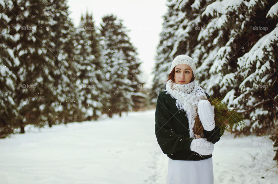 9Winter portrait of young redhead woman in green sweater in snowcovered winter park.