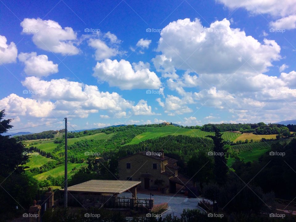 Tuscany countryside, green hills, blue and cloudy sky, rural landscape