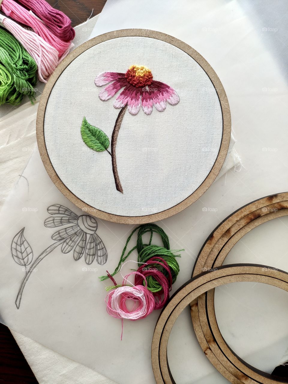 A hand-embroidered flower and the materials used to make it such as: thread, drawing, hoop...