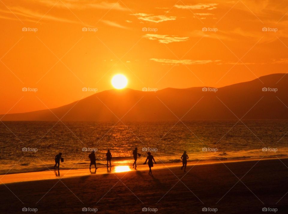 People having fun at the beach during sunset