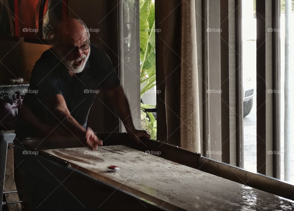 Playing Indoor Shuffleboard. Happy Pub Patron Playing Shuffleboard
