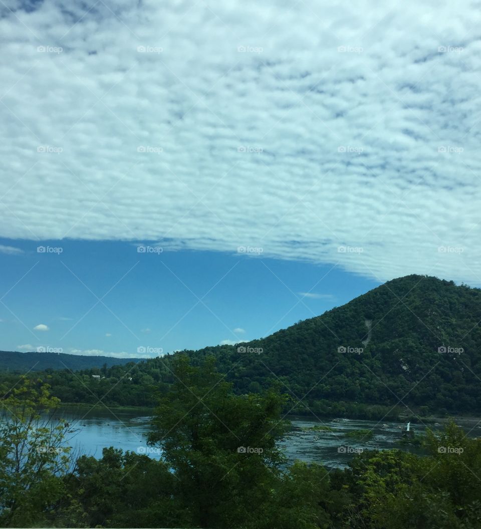 Beautiful water and clouded sky with a pattern. Mountain in photo. 