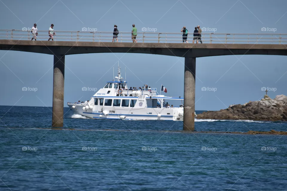 A ship and a bridge in a coastal scenery with sea and horizon