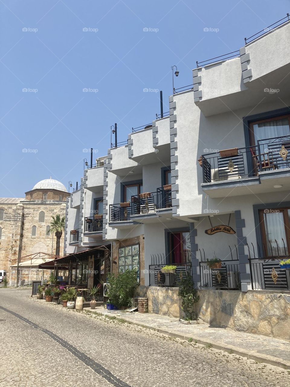 Greek village in Turkey. Blue sky and tall palm trees. Sunsets and sunny days. Summertime in Kusadasi. Vacation travel in Turkey . Summer view. Sunny day during vacation