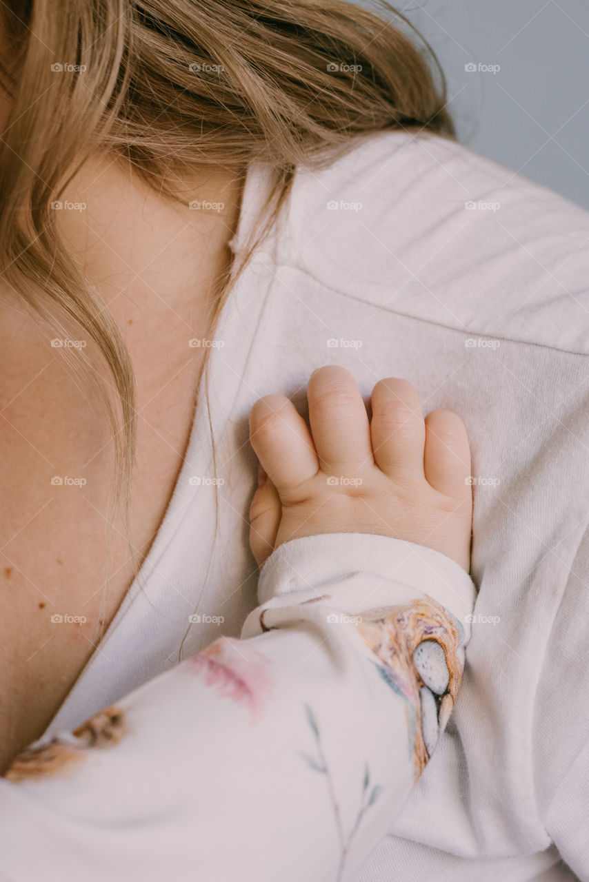 Detail of child’s hand resting on her mum.