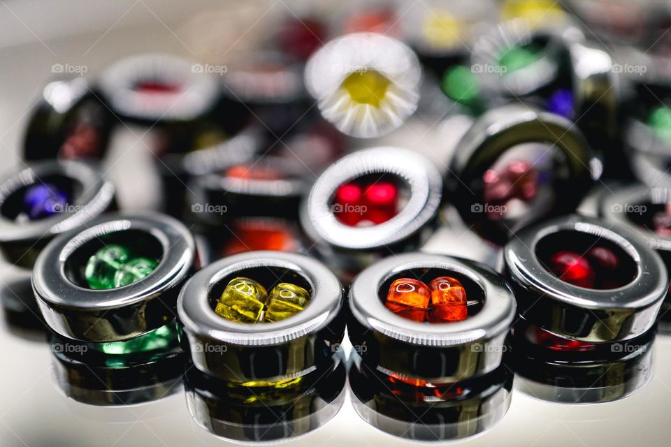 Circular hematite beaded necklace with colorful beads in the center resting on a mirrored surface reflecting beautifully 