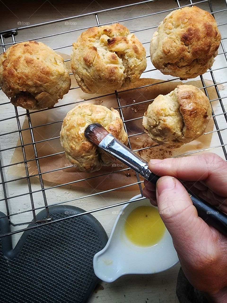 Glazing freshly baked buttermilk biscuits with melted butter.