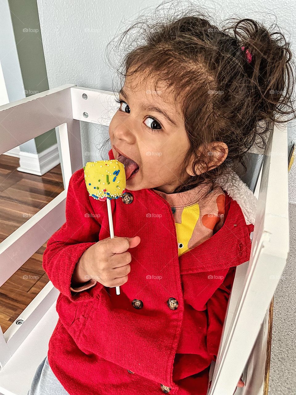 Toddler girl eating cake pop, eating delicious cake pops at home, toddler enjoys treats from Mommy, kids eating desserts 