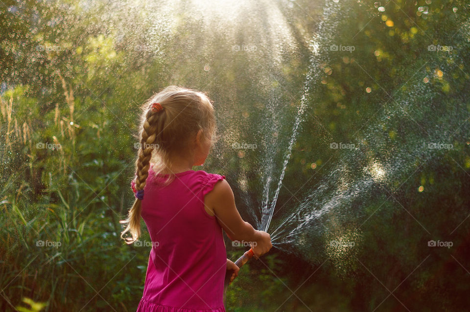 Girl waters plants in the garden