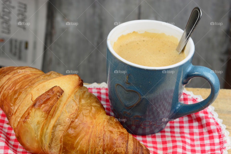 cup of coffee with a croissant bread