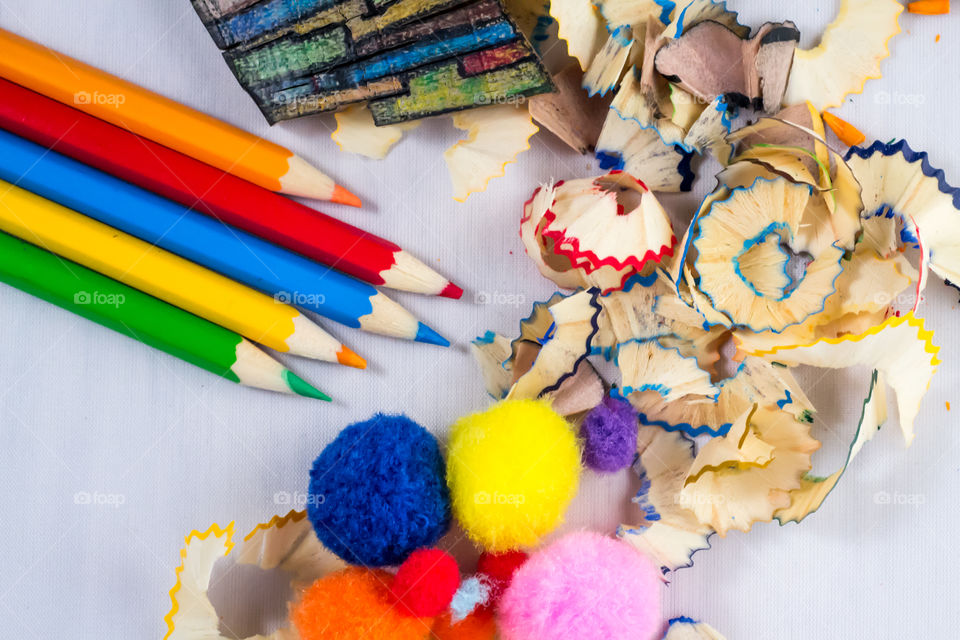 Crayons and fluffy little balls in white background