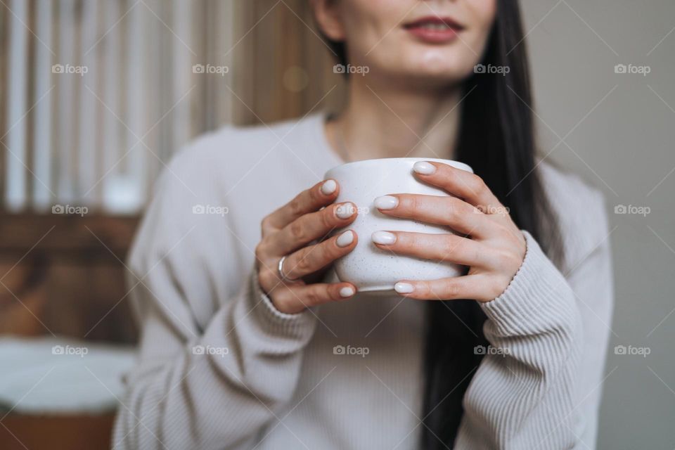 Crop photo of Beautiful smiling woman teenager girl with dark long hair in home clothes with the morning cup of coffee