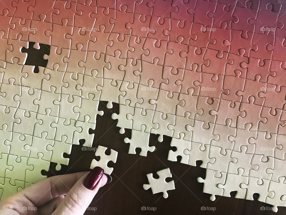 Young woman gathering pink puzzles at leisure time 