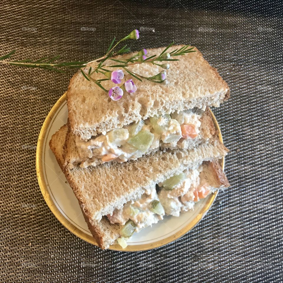 A healthy tunafish salad sandwich on white bread with celery and red bell peppers for lunch, with a purple flower . USA, America 