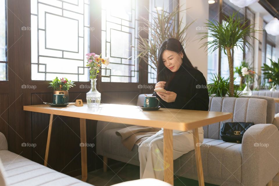 Young Asian woman using social media in cafe