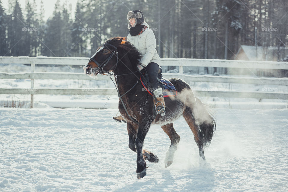 Teenage girl horseback jumping at cold winter day 