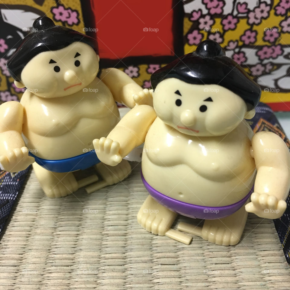 Wind up sumo wrestlers with cherry blossoms in the background. This picture is of Japanese souvenirs that happen to be wind up and sumos. 