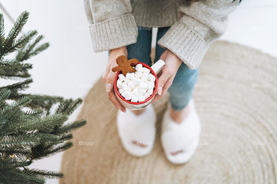 Young woman with cup of hot drink at home in Christmas time 