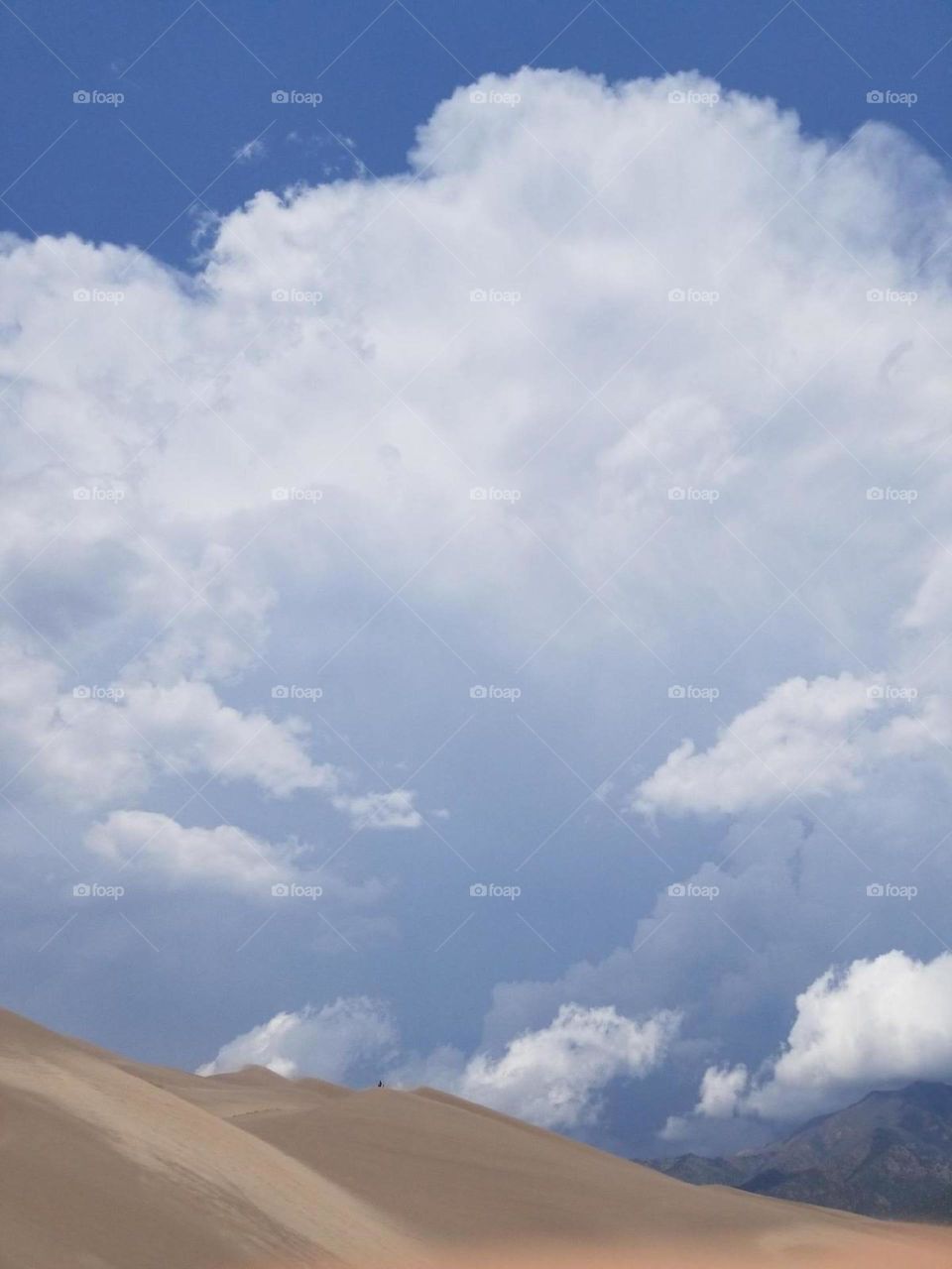 white fluffy clouds hanging over the sand dunes