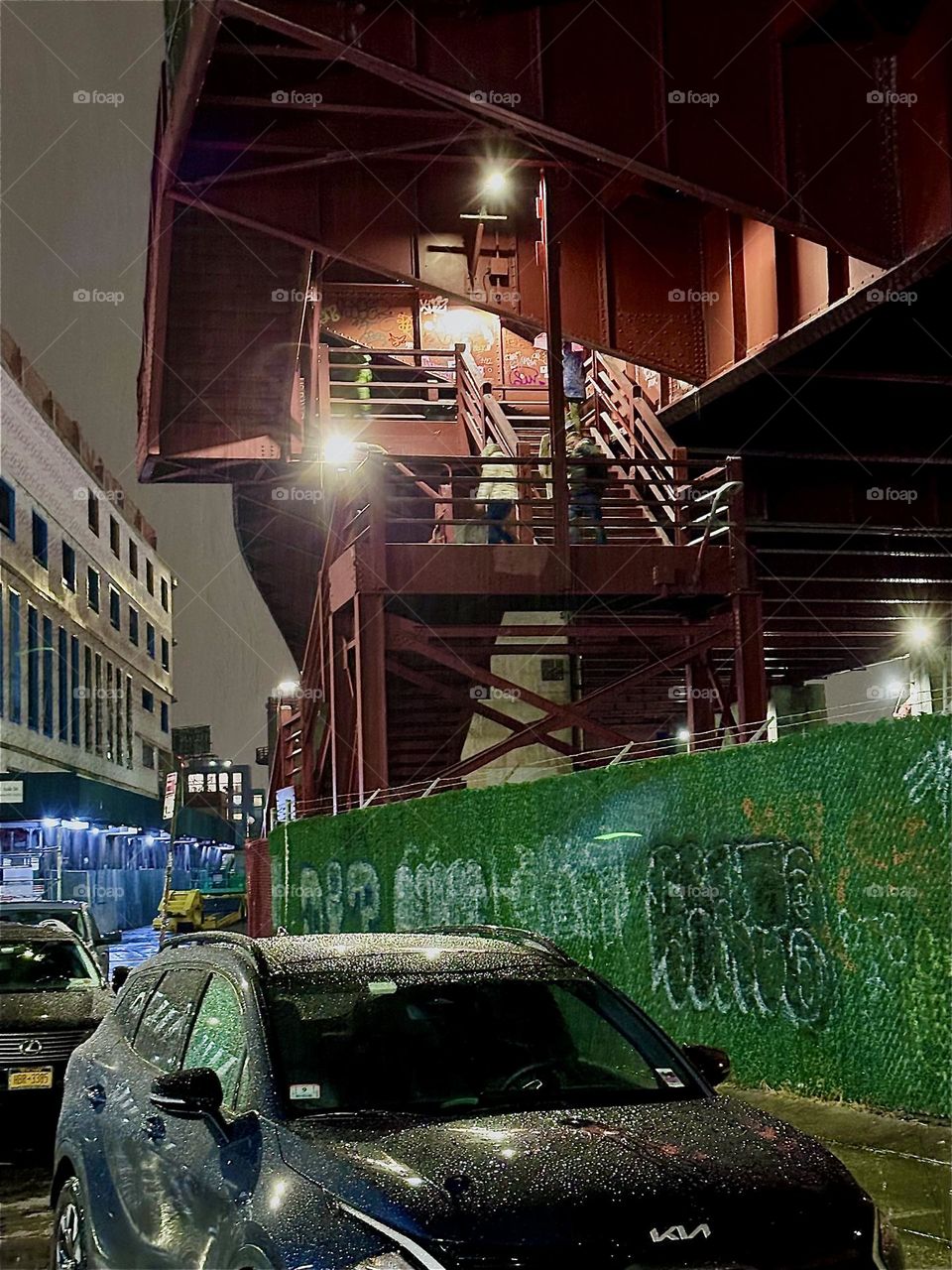 This is the illuminated staircase of the “Pulaski Bridge” at “Newtown Creek” in “Greenpoint”, Brooklyn at night with people ascending on it to be on their way to cross the bridge. 2023. Hypnotic Productions