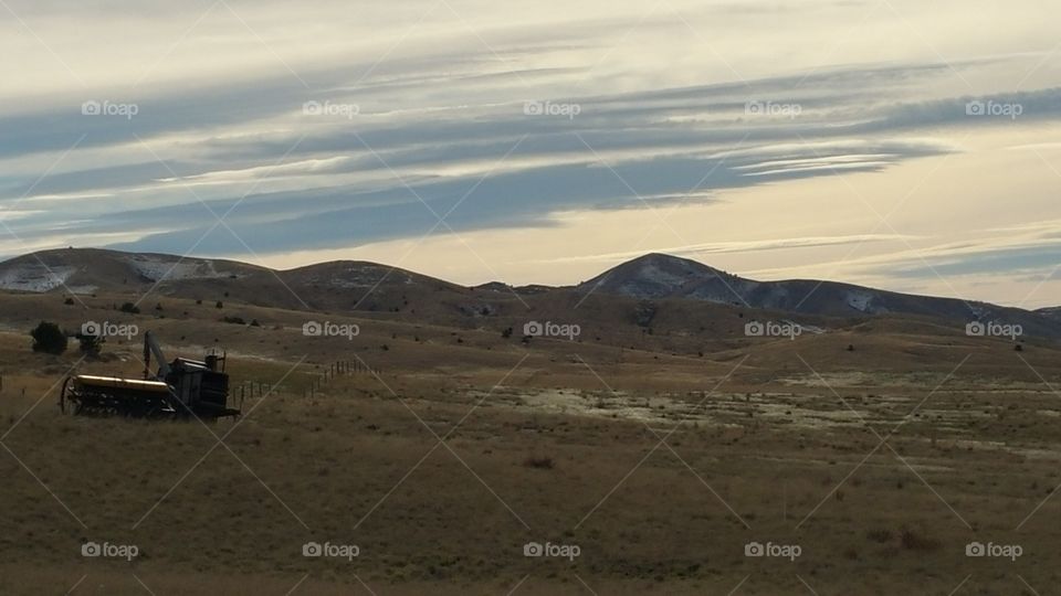 field in the Montana mountains with old farm equipment