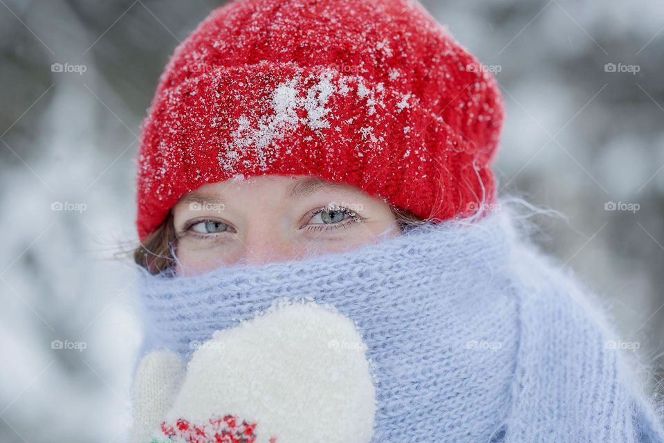 A young girl on a walk in a winter park, a hat and scarf covered in snow and even snow on her eyelashes.

￼