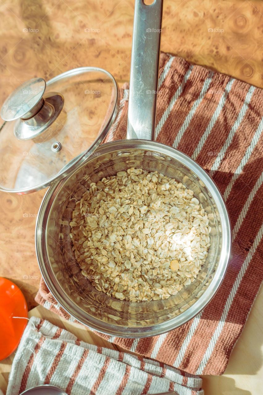 Cooked oatmeal in a deep gray plate with hazelnuts and honey.