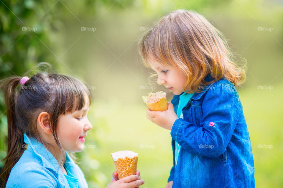 Little sisters eating ice cream in a spring park 